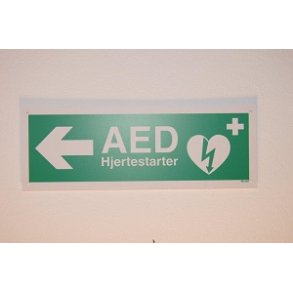 Enkeltsidet skilt til venstre angivelse af retning til AED/hjertestarter